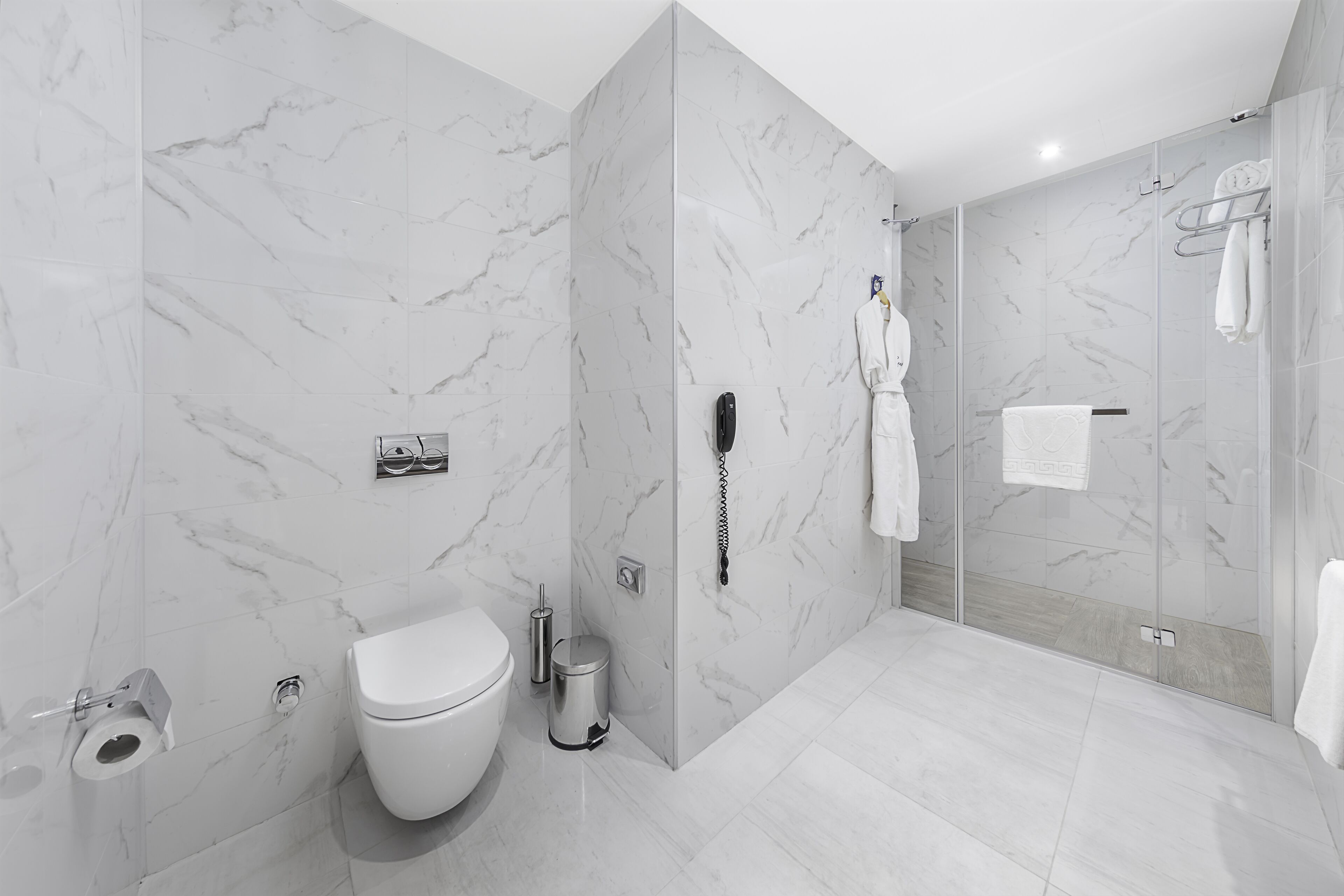 Un baño moderno con inodoro, bidé y zona de ducha con mampara de vidrio.