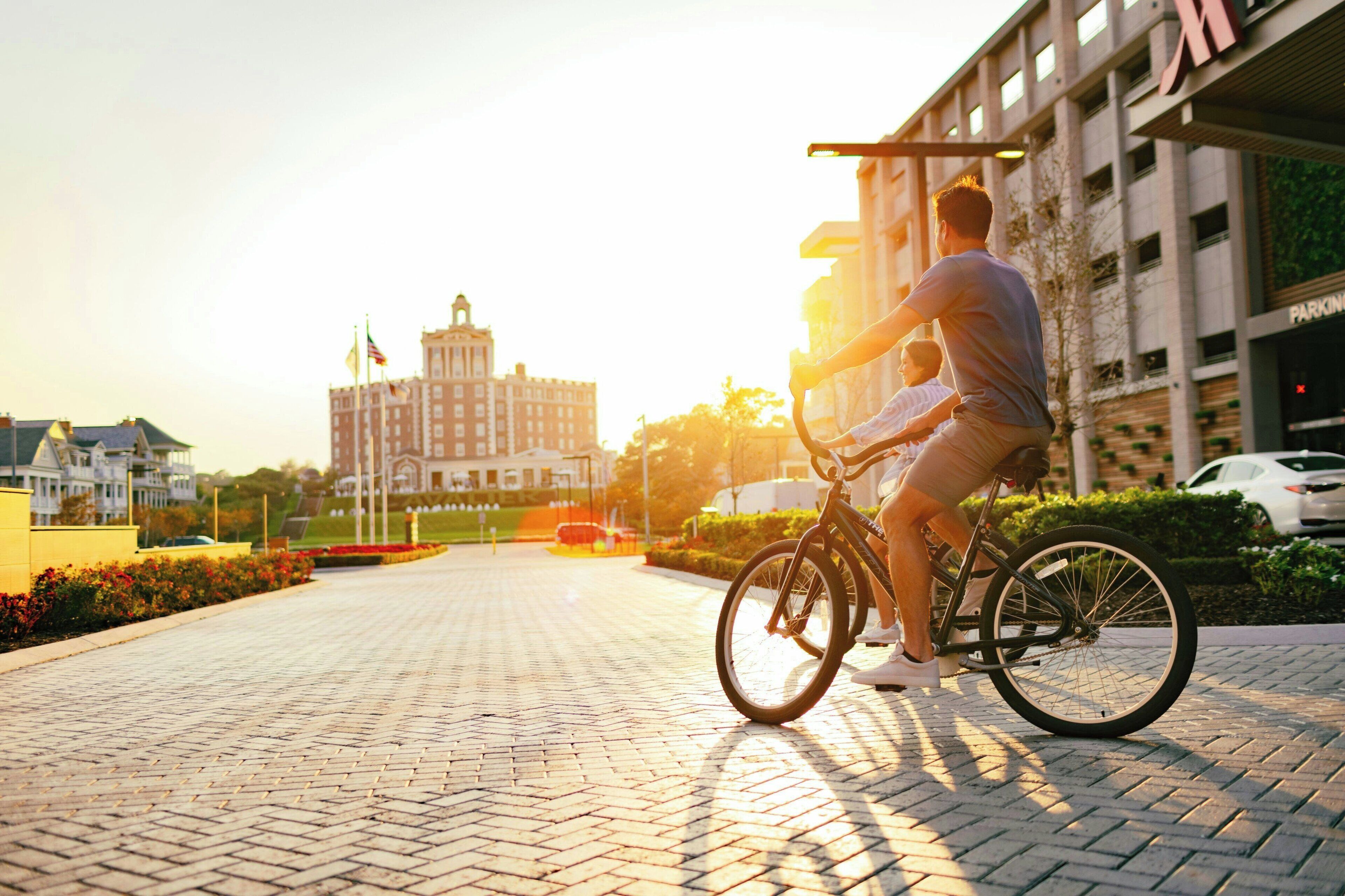 A person riding a bicycle on a paved pathway with a building in the background.
