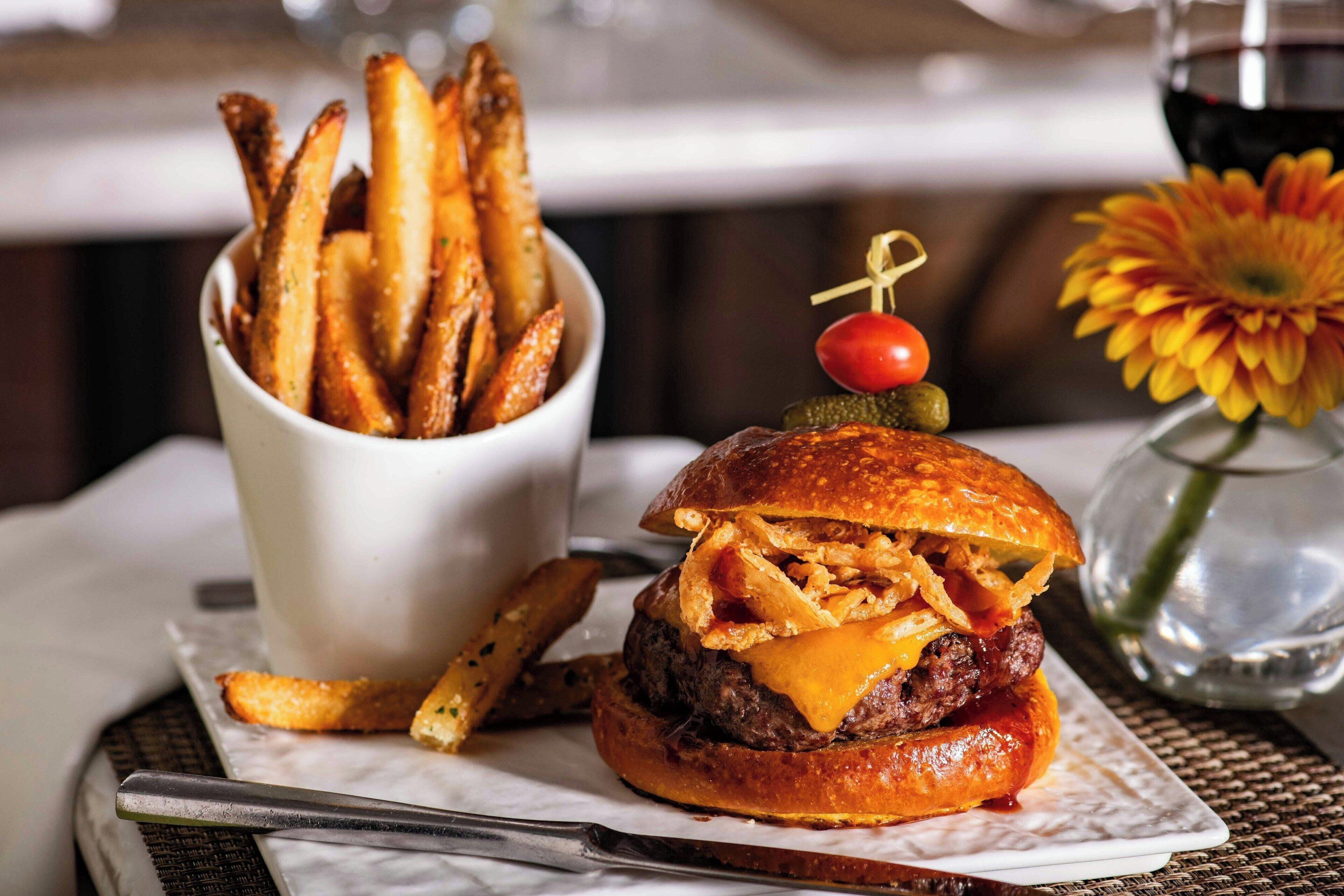 A burger with a cherry and a pickle on top, served with a side of fries.