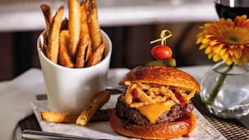 A burger with a cherry and a pickle on top, served with a side of fries.