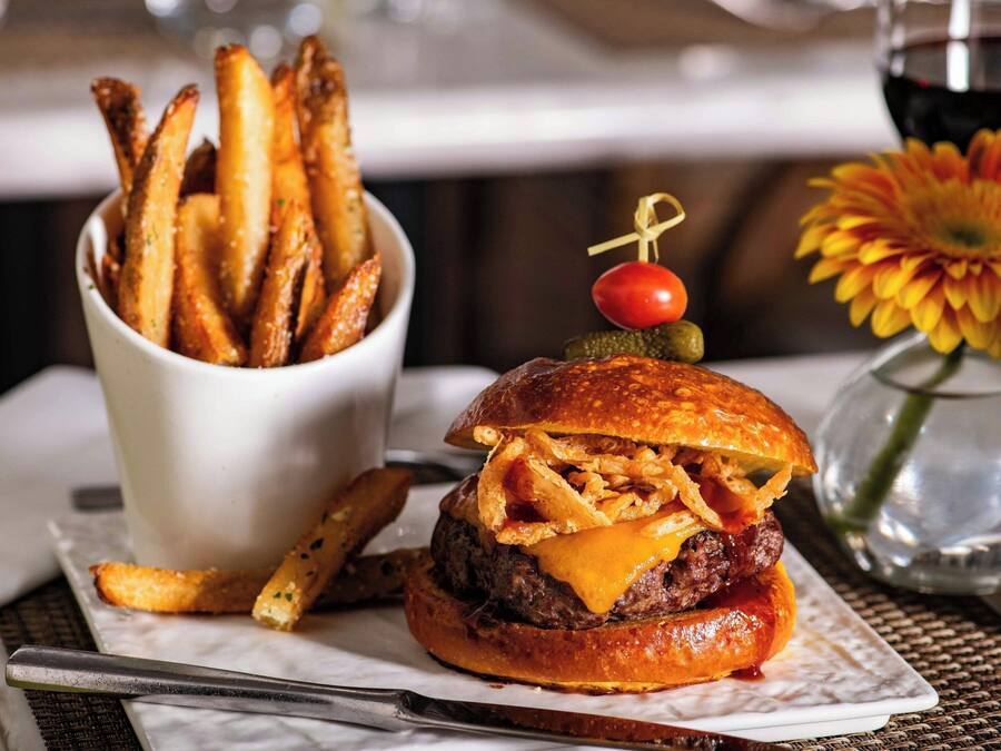 A burger with a cherry and a pickle on top, served with a side of fries.