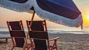 Two beach chairs under a canopy with a view of the ocean at sunset. - The Historic Cavalier Hotel and Beach Club, Autograph Collection (Virginia Beach)