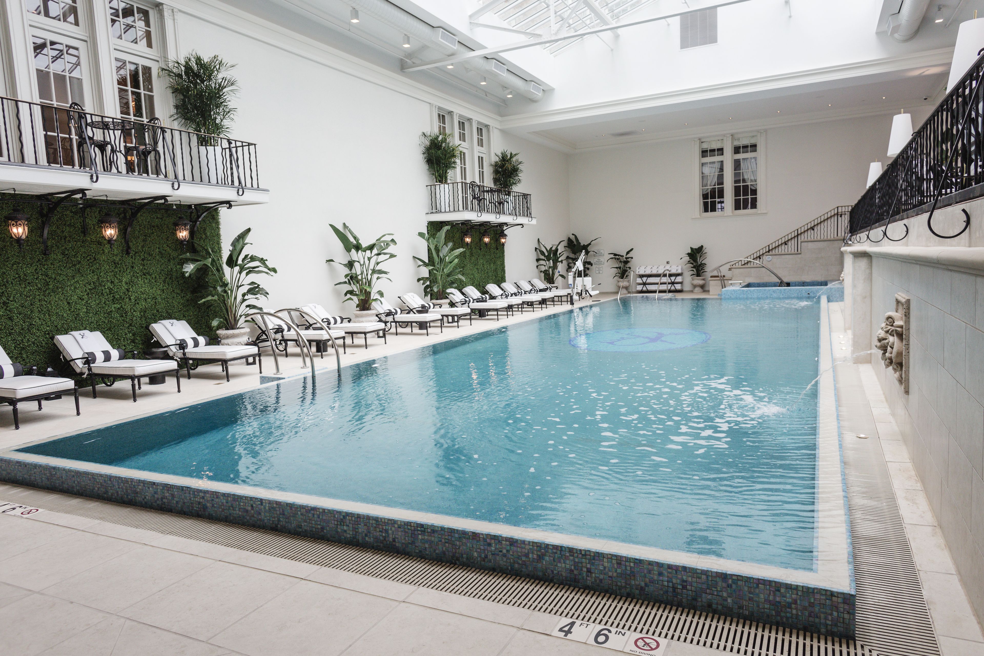 An indoor swimming pool with lounge chairs and a green wall.