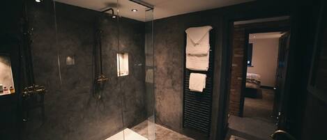 A modern bathroom with a glass-enclosed shower, a large bathtub, and a separate sink area.