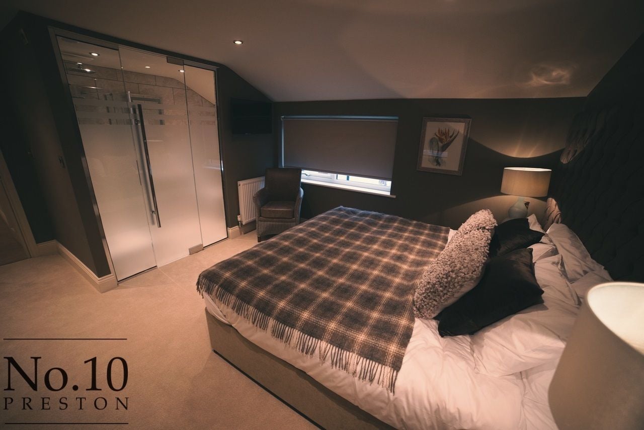 A bedroom with a bed, a chair, a desk, a window, and a wardrobe.