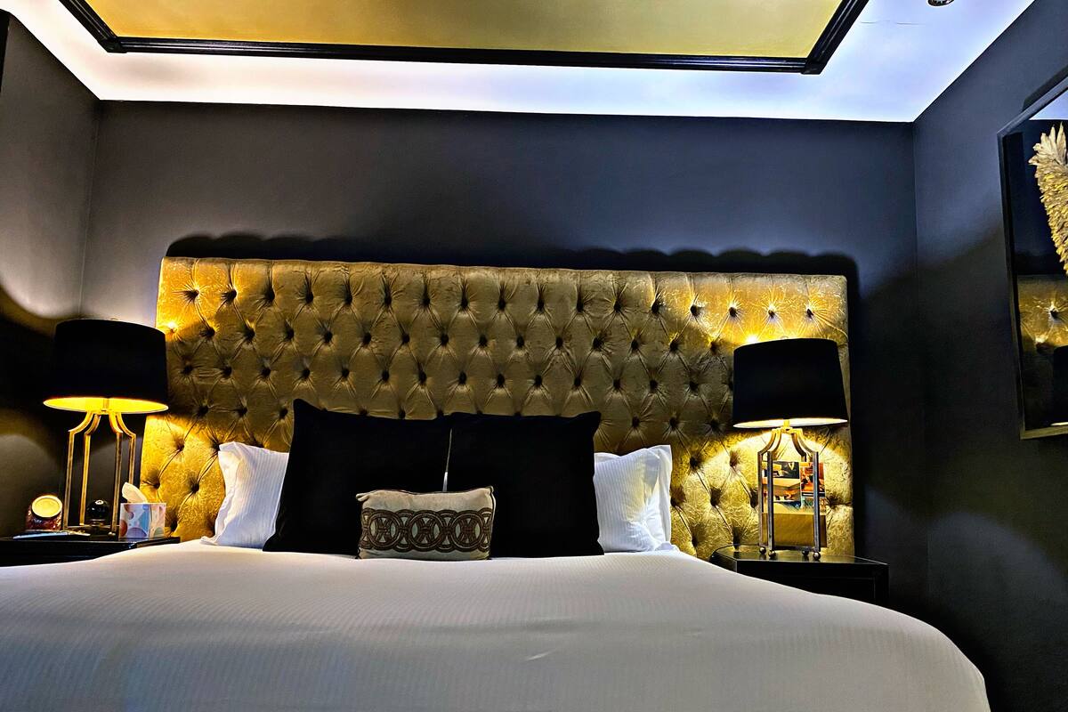 A bedroom with a tufted headboard, a large bed, two bedside tables with lamps, and a ceiling light.