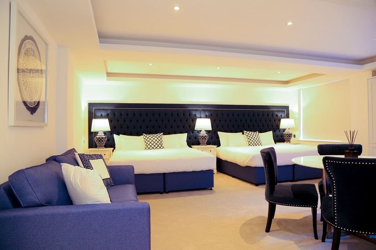 A hotel room with a large bed, a sofa, a dining table, and a chair.