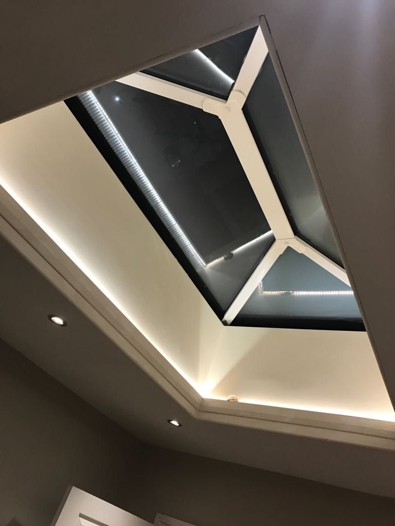 Un techo con iluminación empotrada y un diseño de tragaluz geométrico.