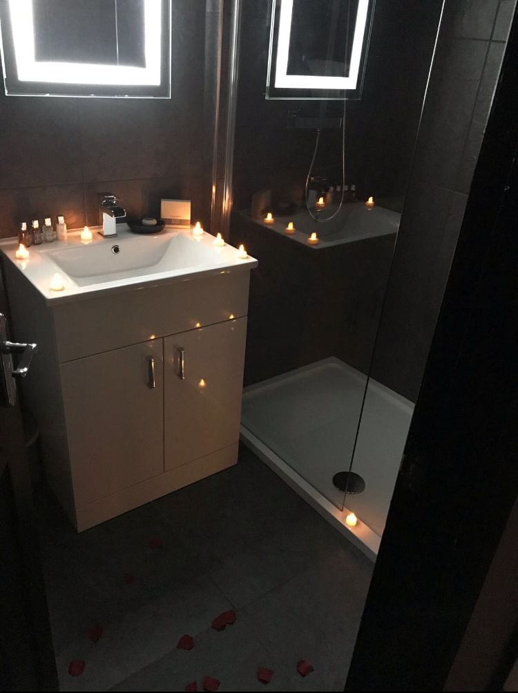 A modern bathroom with a white vanity, a mirror, and a shower area.