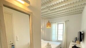 A hotel room with a bed, a desk, a chair, a television, and a window with curtains. - Hotel Lefteris (Mykonos)
