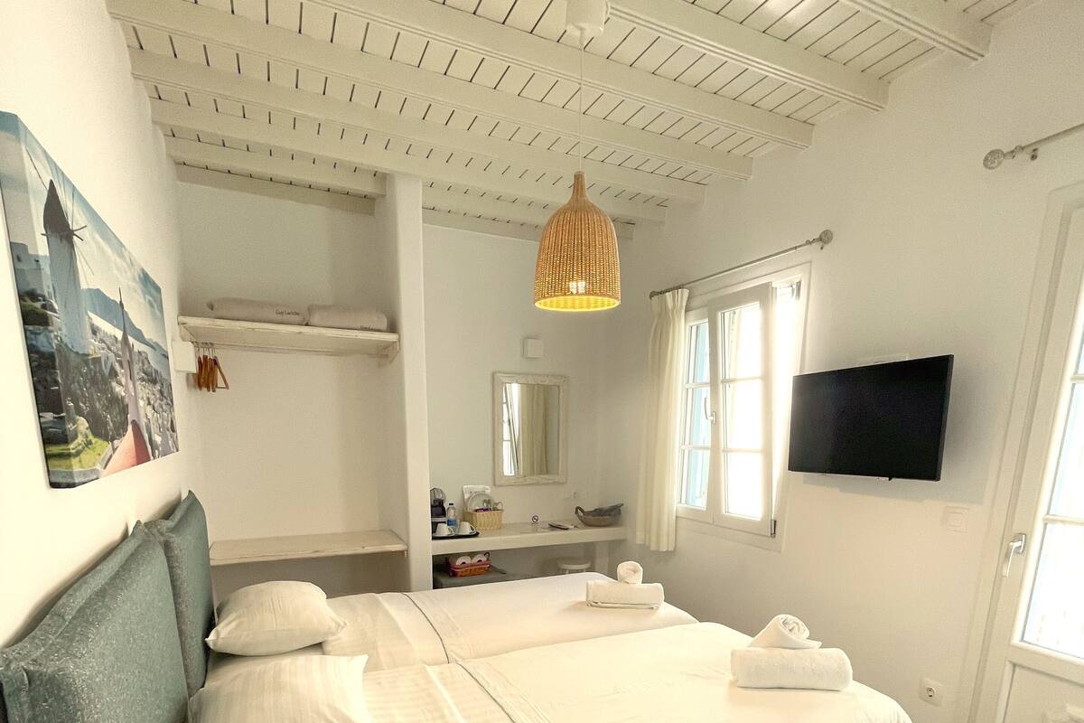Quarto com cama, televisão, janela e luminária no teto.