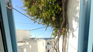 A narrow alleyway with white buildings, blue doors, and a tree with pink flowers. - Hotel Lefteris (Mykonos)