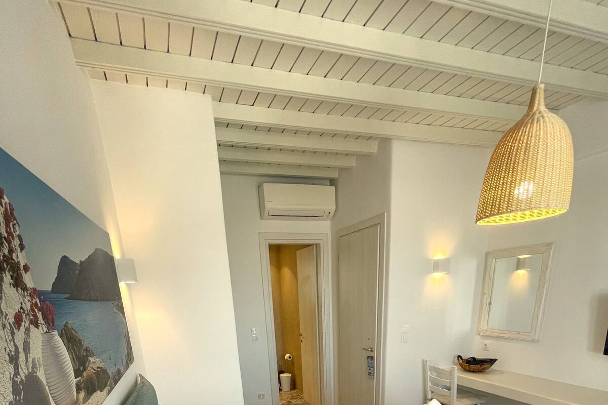 Quarto de hotel com duas camas, uma escrivaninha, um espelho e um candeeiro pendente.