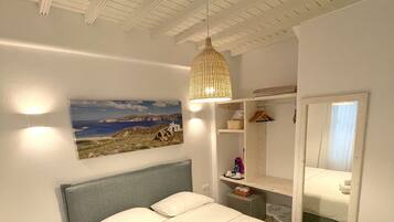 Une chambre à coucher comprenant un lit, un luminaire suspendu, un miroir et une étagère fixée au mur.