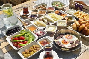 A table with various food items and a pitcher of water. - Balım Sultany (Cesme)