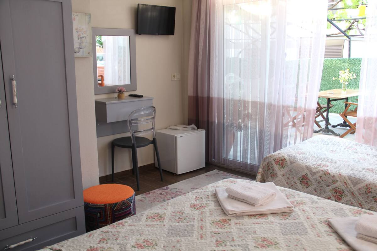 A hotel room with a bed, a desk, a chair, a television, and a window with curtains.