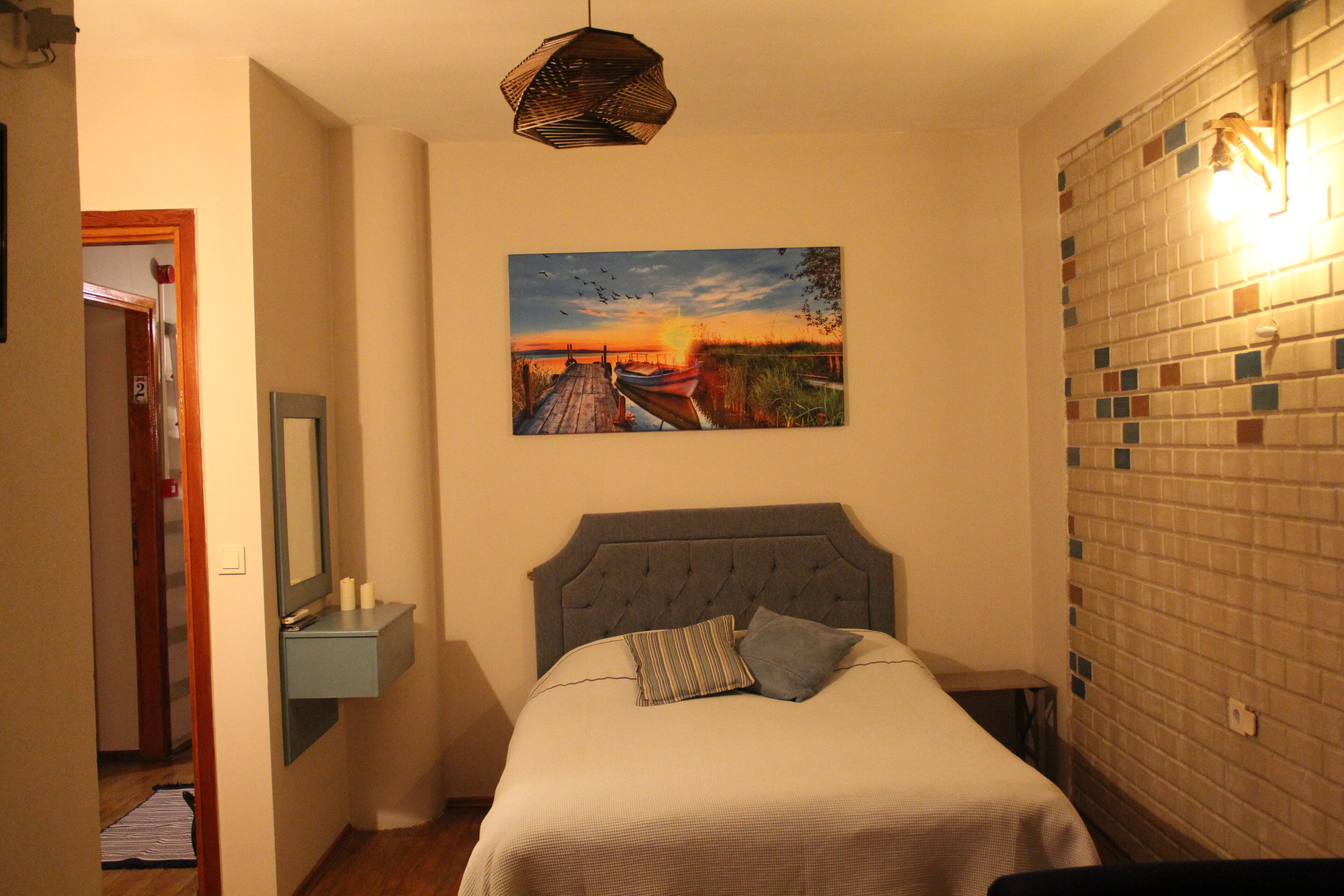 Una camera da letto con un letto, un quadro, un comodino e una parete con motivo a mosaico.