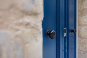 Una puerta azul con un pomo redondo y una placa rectangular, empotrada en una pared de piedra.