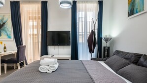 Une chambre d’hôtel avec un grand lit, un bureau avec une chaise, une télévision et un tableau au mur.