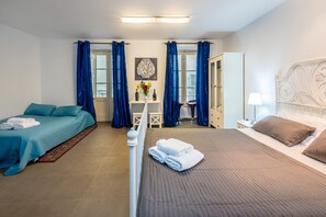 Una habitación de hotel con cama, mesita de noche, silla, armario y ventana con cortinas.