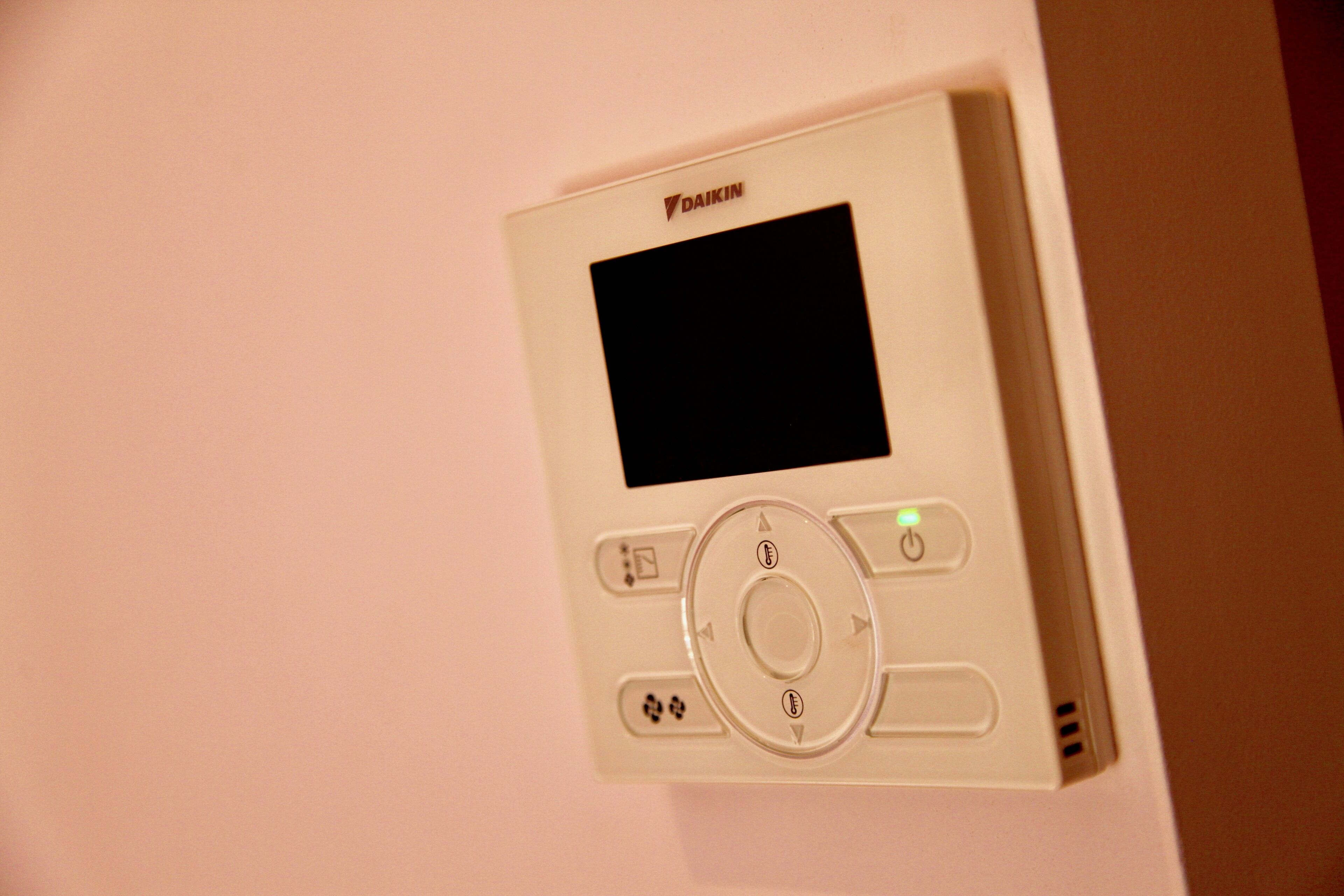 Un dispositivo electrónico blanco con pantalla y botones, fijado a la pared.
