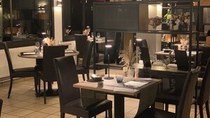 Interior de un restaurante con mesas, sillas y una zona de bar.