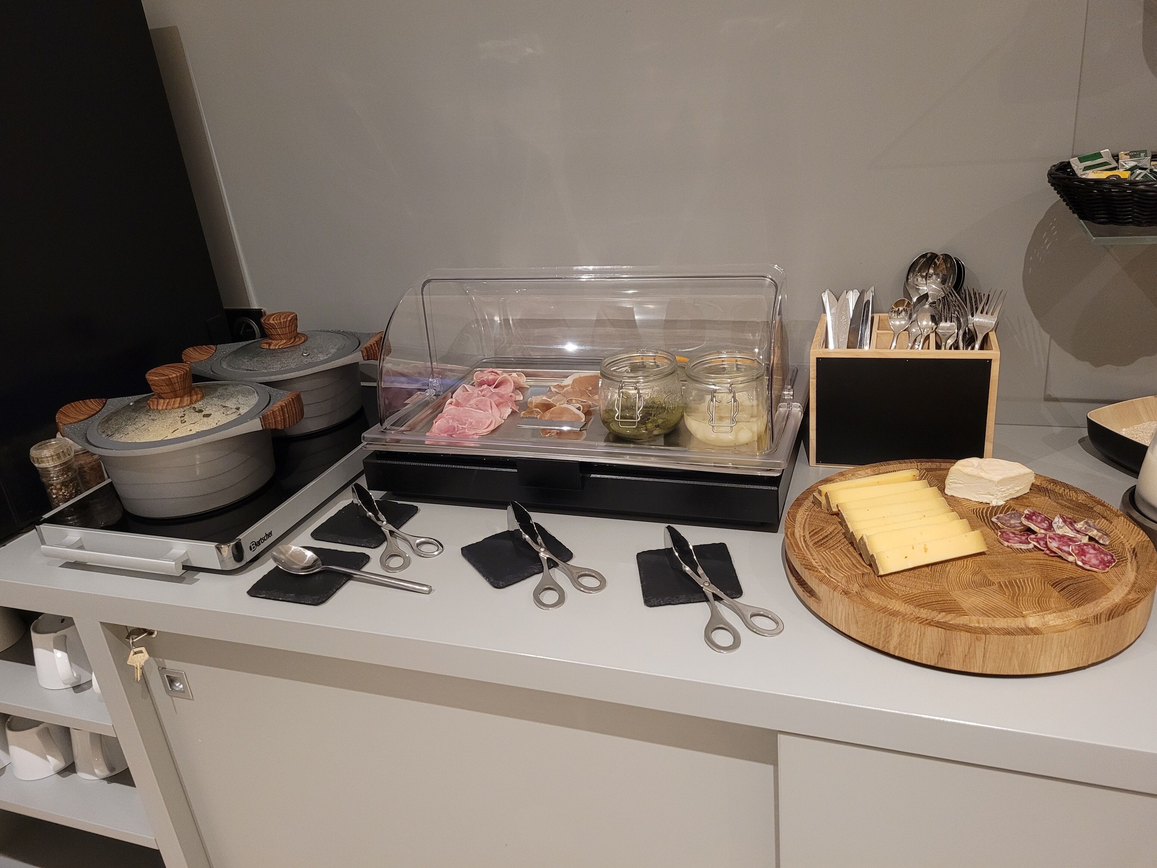 Montaje de bufé con diversos alimentos, utensilios y recipientes.