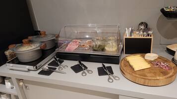 Montaje de bufé con diversos alimentos, utensilios y recipientes.