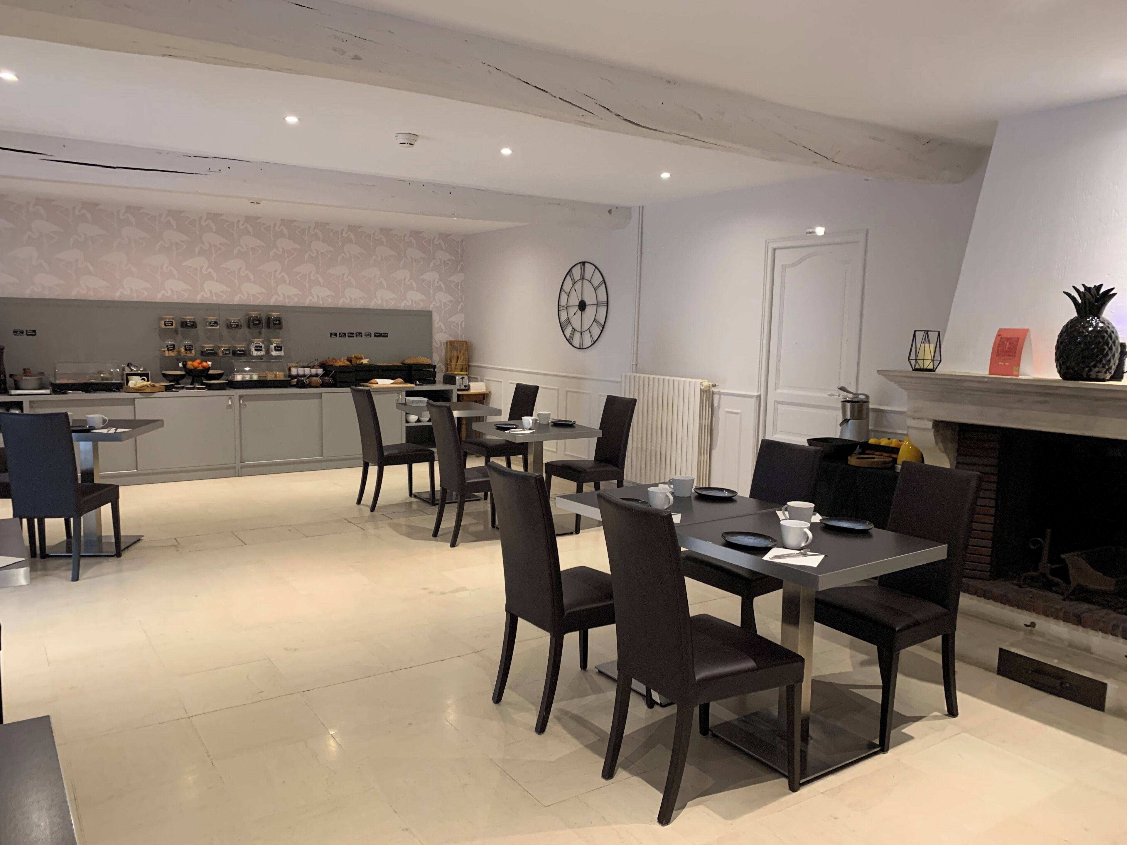 Un comedor moderno con cocina al fondo, que incluye un reloj, una chimenea y diversas opciones de asientos.