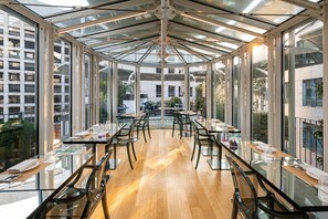 A modern restaurant with glass tables and chairs, large windows, and a wooden floor. - The Street Milano Duomo | a Design Boutique Hotel (Milan)
