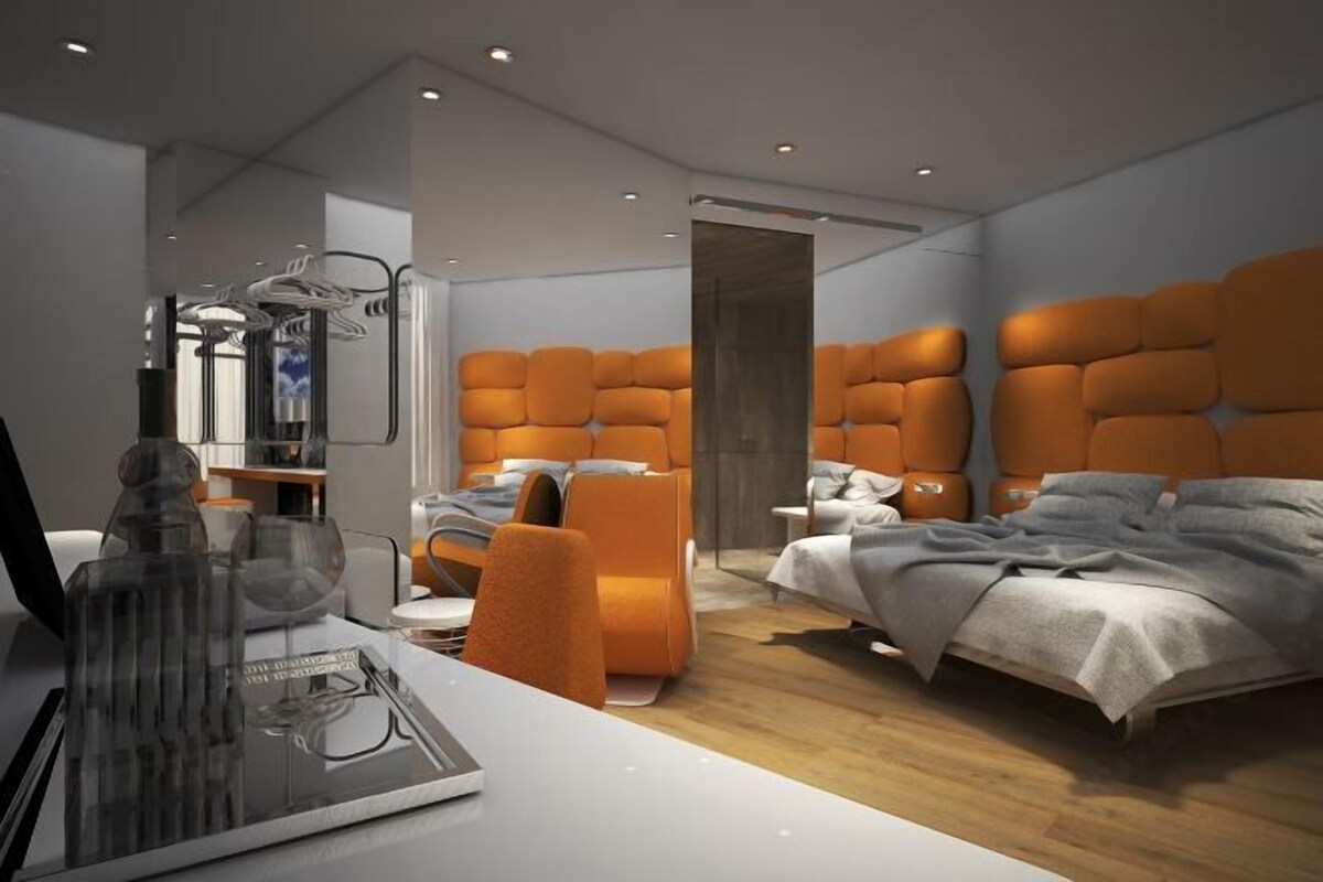 Une chambre moderne avec deux lits, un coin salon et un bureau agrémenté d’une sculpture en verre.