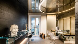 Un interior moderno con un escritorio de cristal, una silla blanca y un ventanal grande.