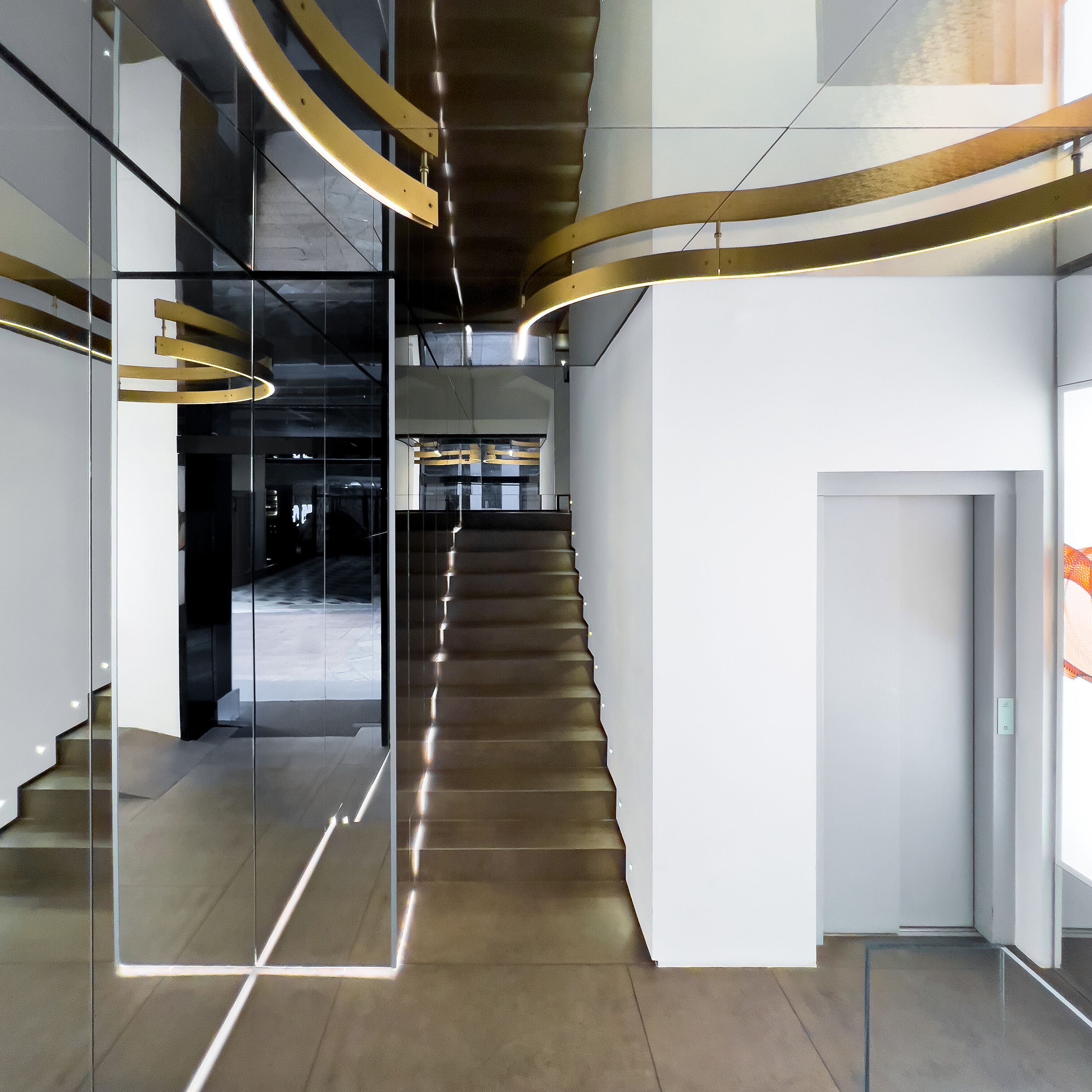 A modern interior with a staircase, glass partitions, and contemporary lighting fixtures.