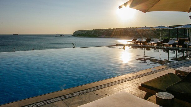 Ein Pool ohne Rand mit Blick auf das Meer und einen Sonnenuntergang.