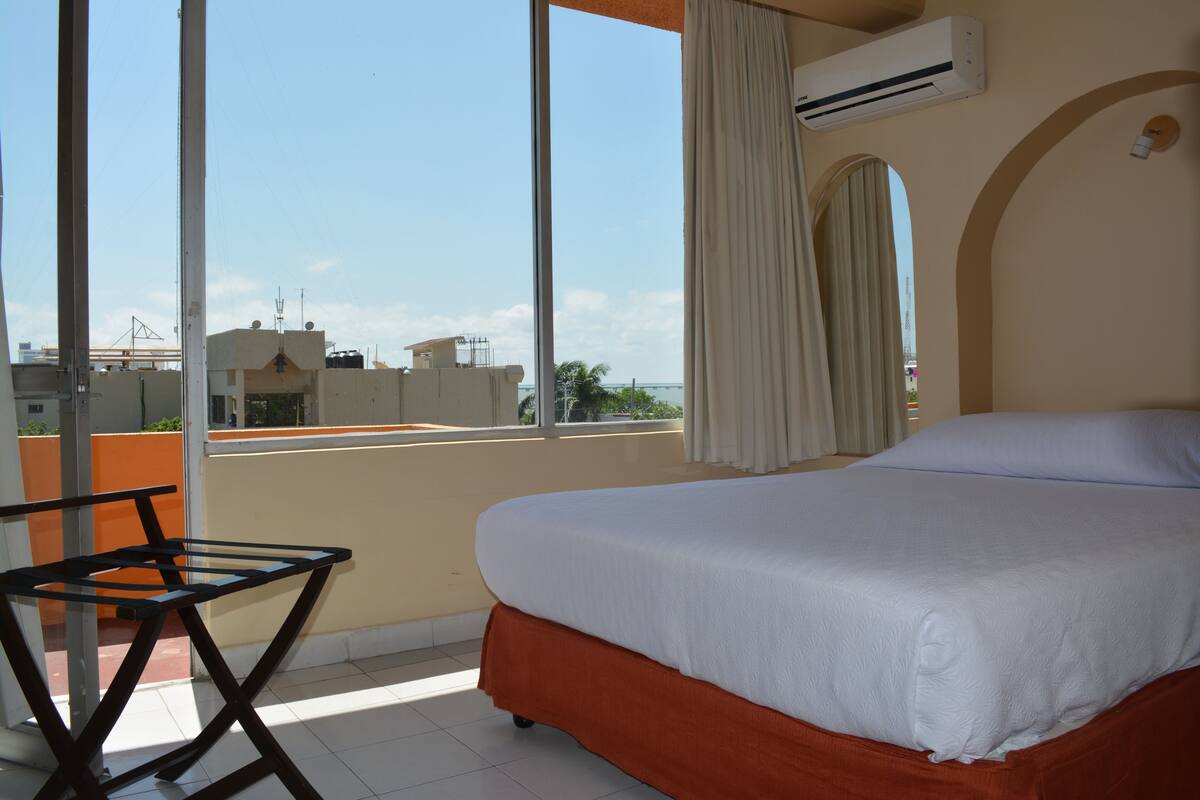 Une chambre d’hôtel avec un lit, une table et une vue sur la ville.