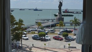 Vista desde una ventana sobre un puerto deportivo con barcos, una estatua y un aparcamiento.
