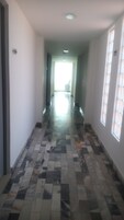 A hallway with patterned floor tiles, a ceiling light, and a window on the right.
