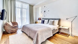 Un dormitorio moderno con una cama grande, un sillón redondo, una mesita de noche y un reloj de pared.