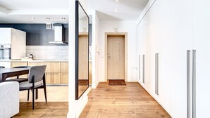 Una cocina moderna con armarios de madera, un comedor con mesa y sillas, y un pasillo que conduce a una puerta.
