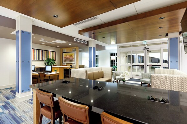 A spacious lobby with a large central table, seating area, and a reception desk.