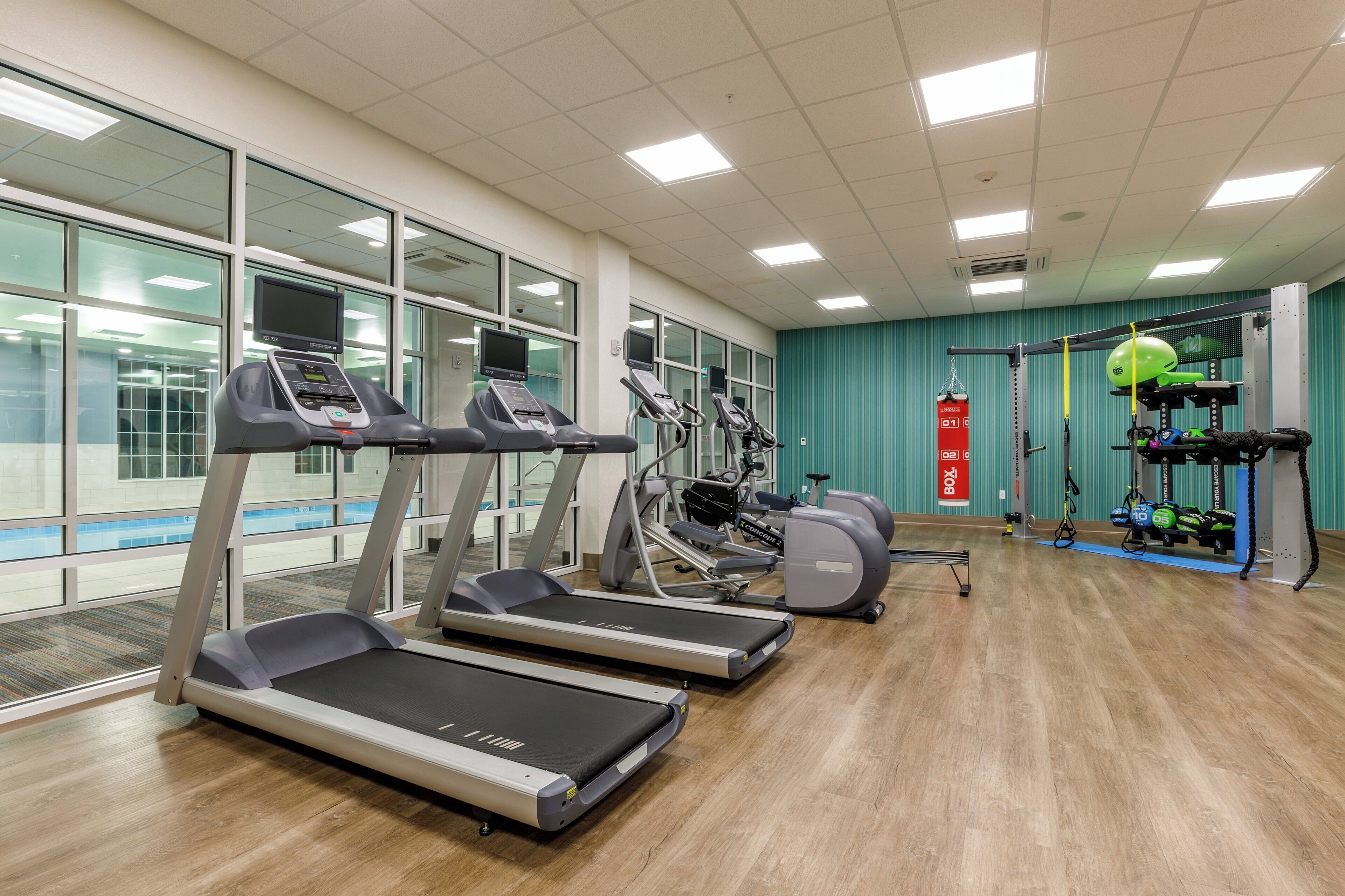 A gym with treadmills, ellipticals, and a weightlifting area.