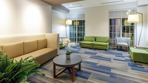 A hotel lobby with a sofa, chairs, a coffee table, and a patterned carpet.