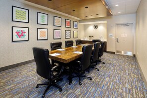 A conference room with a long table, black chairs, and framed artwork on the walls.
