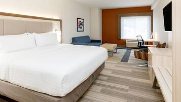Una habitación de hotel con una cama grande, un escritorio, una silla y un sofá.
