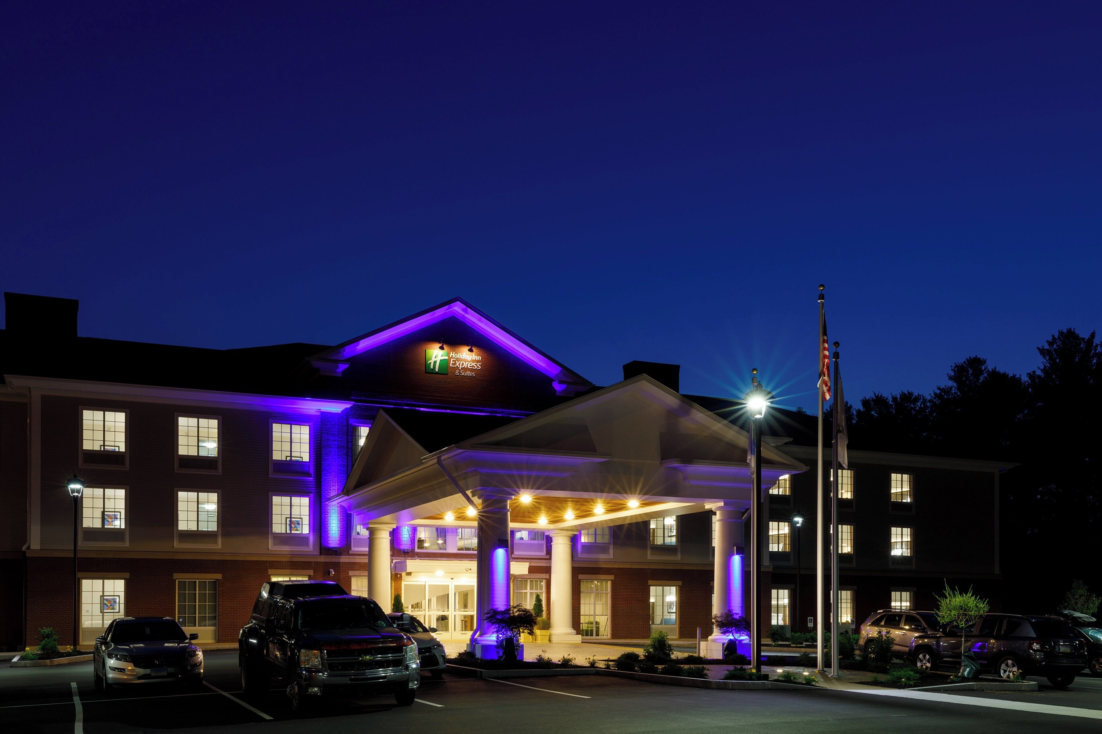 A Holiday Inn Express hotel with a covered entrance, multiple parking spaces, and a flagpole.