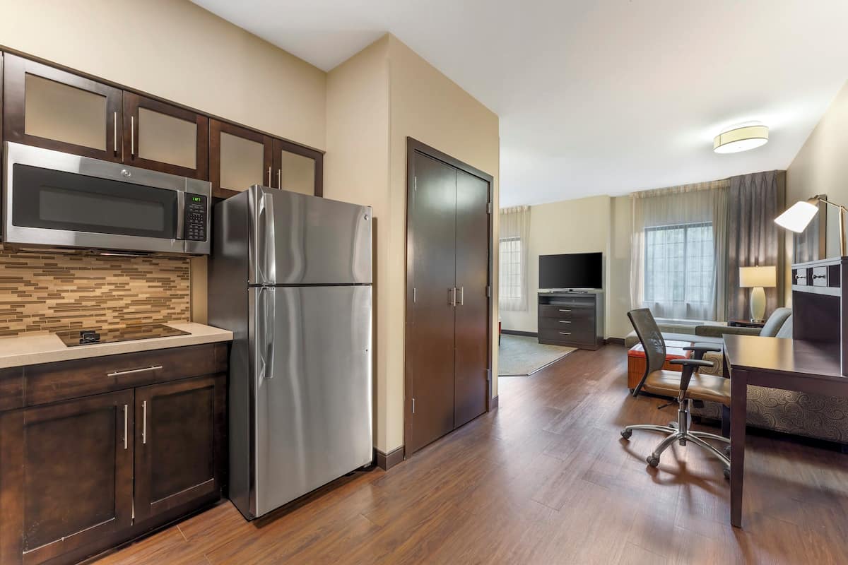 A compact kitchen with a microwave, refrigerator, and wooden cabinets.
