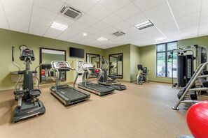 Un gimnasio con cintas de correr, elípticas y equipo de pesas.
