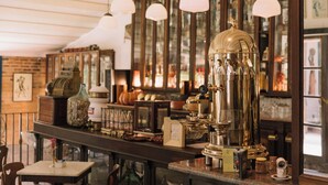Eine Bar mit einem klassischen Espressomaschine, Holzböden mit Flaschen und hängenden Pendelleuchten.
