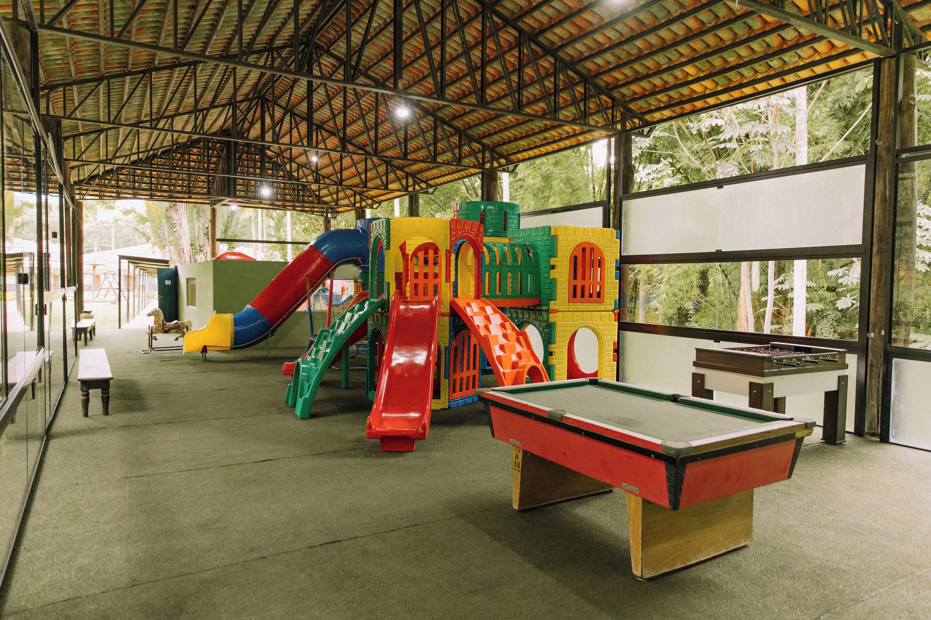 A recreational area with a pool table, colorful play structures, and a slide.