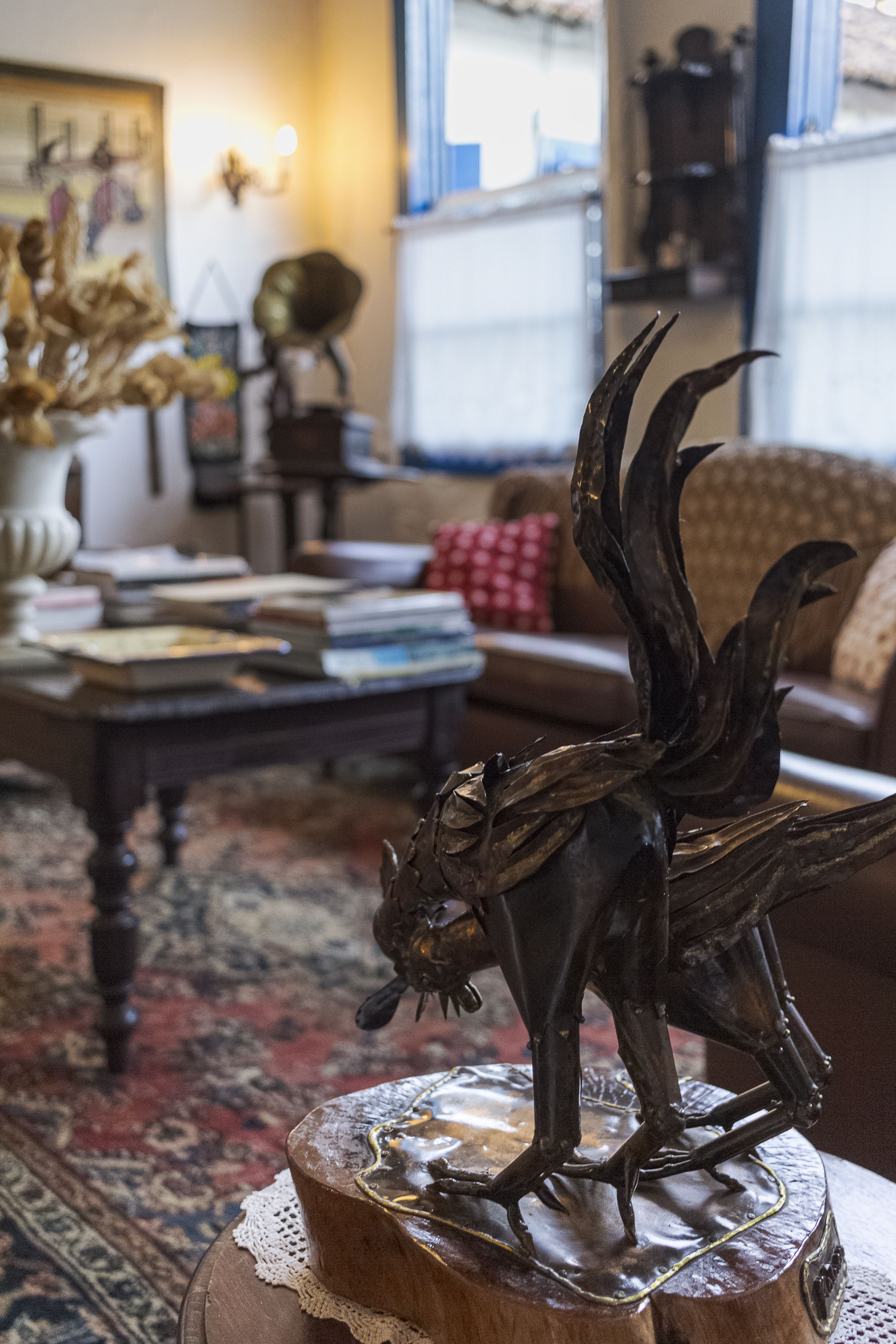 Een woonkamer met een houten salontafel, een bank en een decoratieve metalen sculptuur.